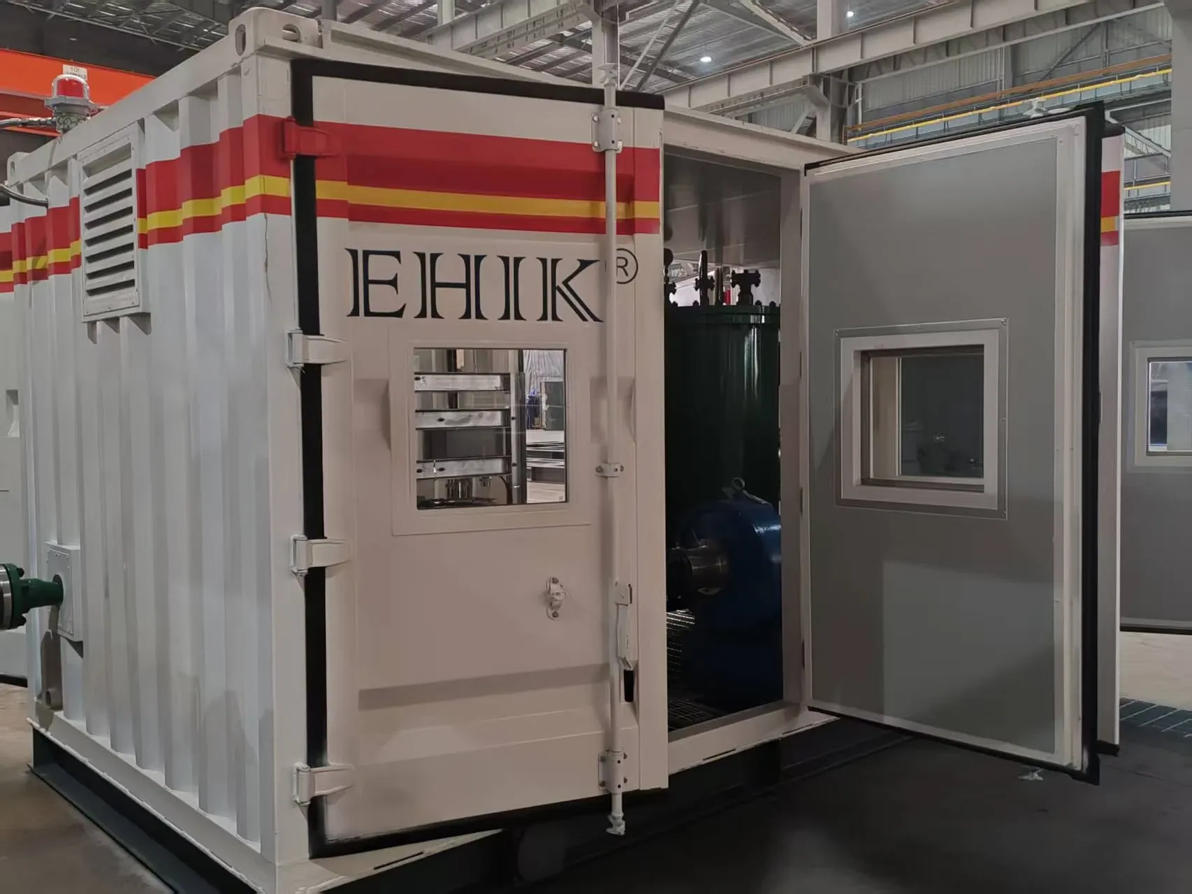 廠房內帶 EHIK 標識的封閉式泵送裝置，可通過打開的門看到泵組。