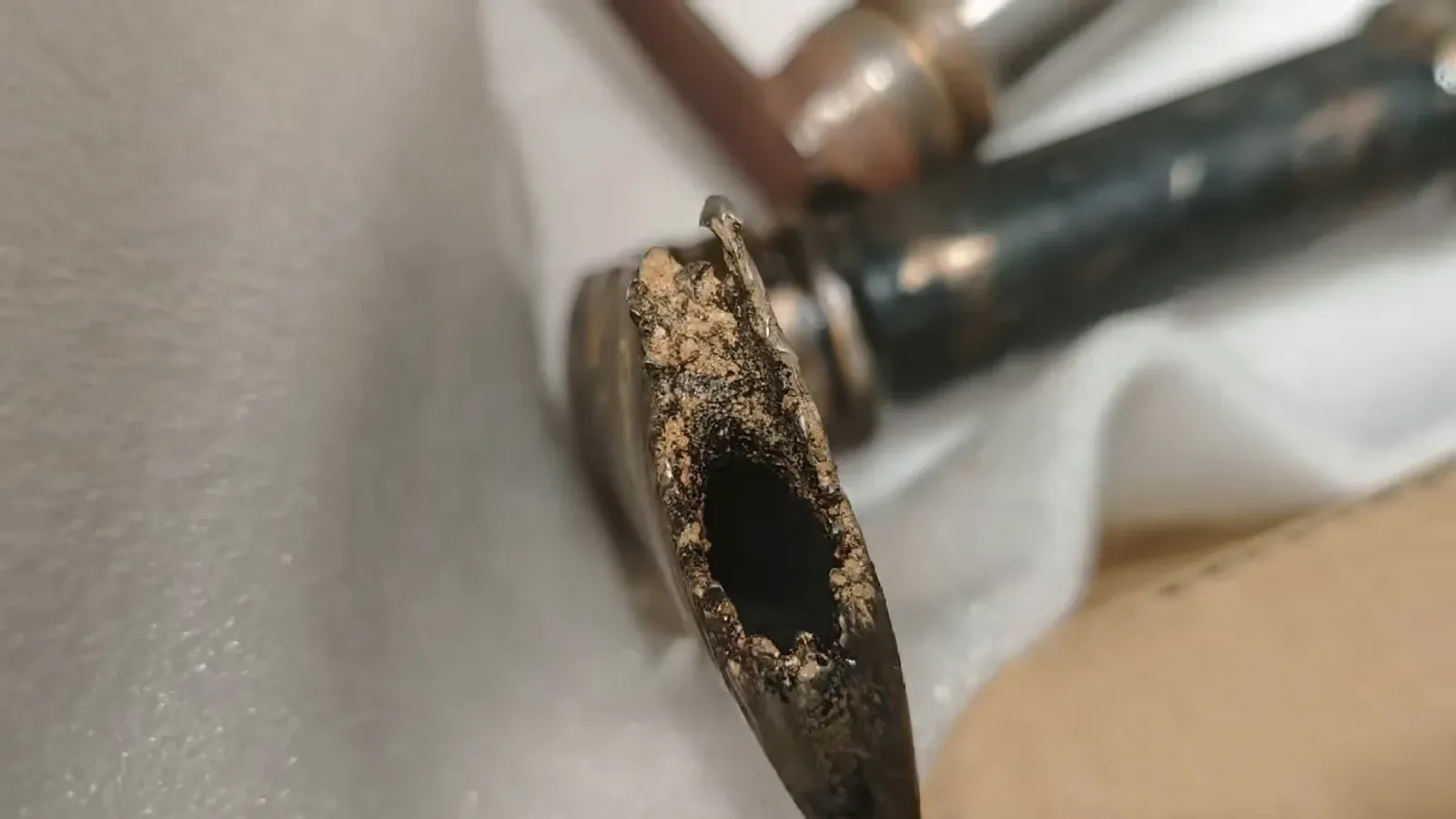 Close-up of a worn pickup tube inlet with visible material loss around the opening.